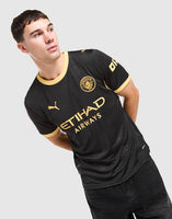 A man wearing a black Puma Etihad Airways Manchester City 2026/27 Away Jersey  with gold trim and logos, posed against a light gray background.