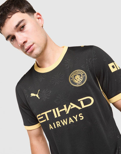 Close-up of a man wearing a black Manchester City 2026/27 Away Jersey  with gold Puma logo, Manchester City crest, and gold Etihad Airways sponsor text.