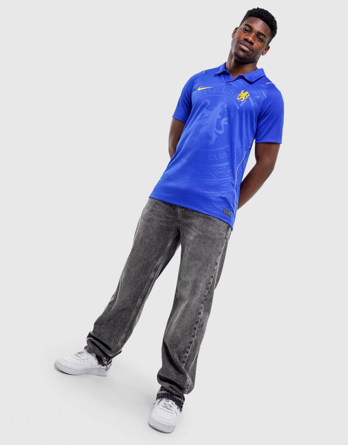 A man wearing a royal blue Nike Chelsea FC 2026/27 Home Shirt, featuring the Chelsea FC crest and a yellow Nike swoosh, posed against a light gray background.