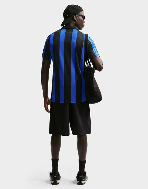 A man shown from the back wearing a Nike Inter Milan 2026/27 Stadium Home Dri-FIT Soccer Replica Jersey, black shorts, black socks, and black sneakers, carrying a black tote bag against a light gray studio background.