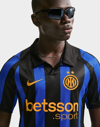 A man wearing a Nike Inter Milan 2026/27 Stadium Home Dri-FIT Soccer Replica Jersey with blue and black vertical stripes, featuring the Inter Milan crest, a gold Nike swoosh, and a Betsson .sport sponsor logo.