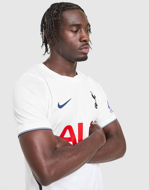 A man wearing a white Nike Tottenham Hotspur 2026/27 Stadium Home Dri-FIT Soccer Jersey with red and blue accents, posed against a light gray background.