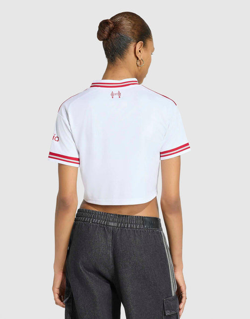 A woman shown from the back wearing a adidas Liverpool FC 26/27 Away Jersey Crop top with red stripes on the collar, shoulders, and cuffs, paired with dark gray jogger pants against a light gray studio background.