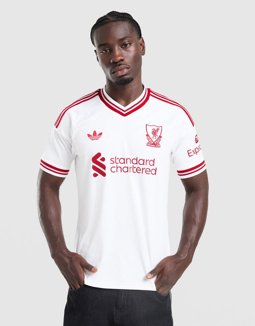 A man modeling a white adidas Liverpool FC 26/27 Away Jersey with red stripes and logos, including the standard chartered sponsor logo, against a light gray background.