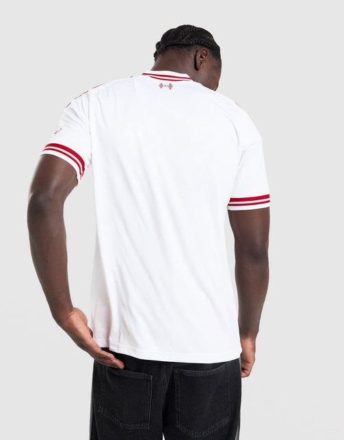 A man viewed from behind wearing a adidas Liverpool FC 26/27 Away Jersey with red stripes on the collar and sleeve cuffs, paired with dark jeans, against a light gray studio background.
